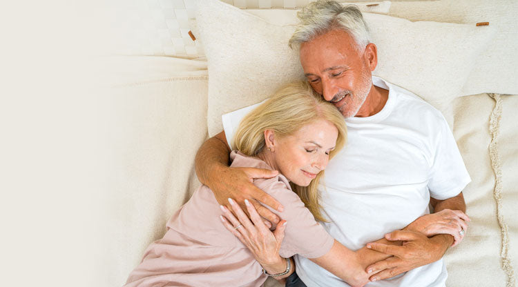 Couple holding onto each other tightly and smiling on a bed