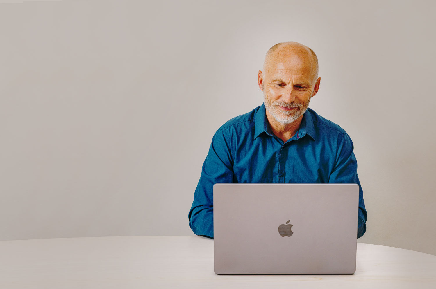 Man sitting on a table looking at his Apple computer