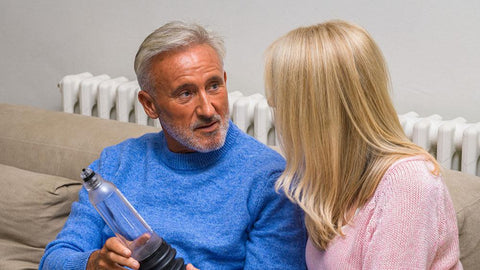 Man talking to women while holding a VaxAid Penis pump