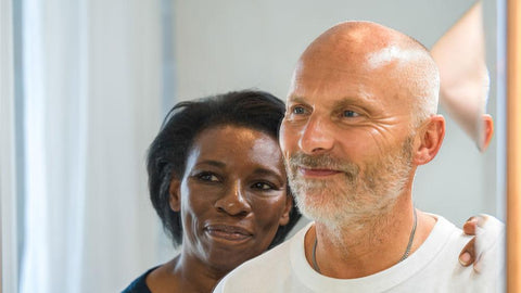 Man looking into a mirror with a smiling women behind him